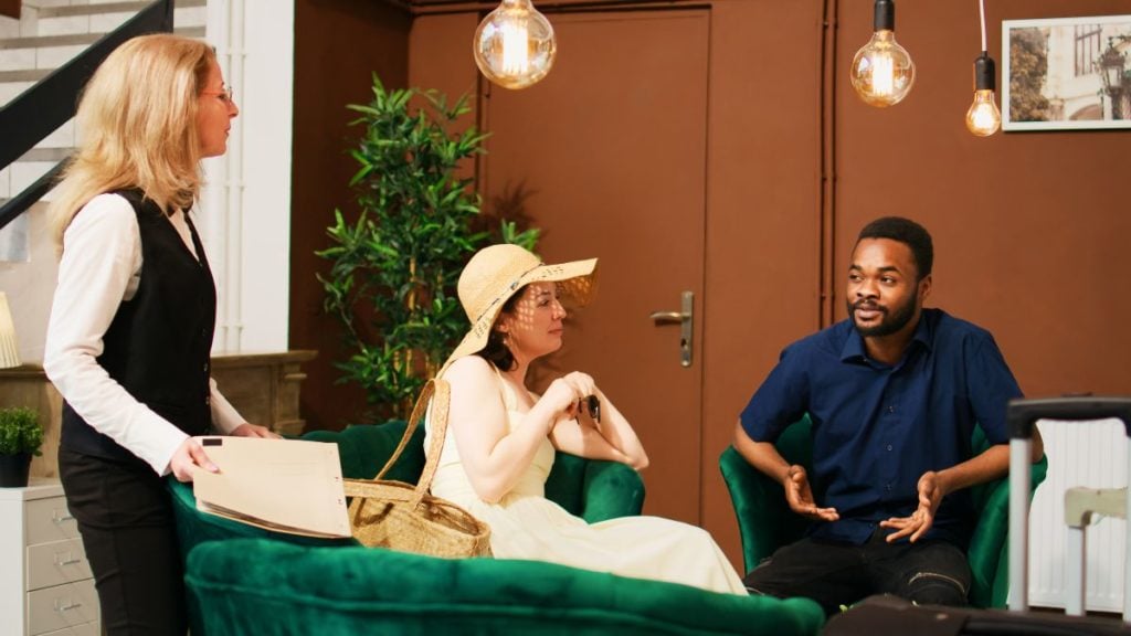 porteiro conversando com dois moradores no salão de entrada do prédio.