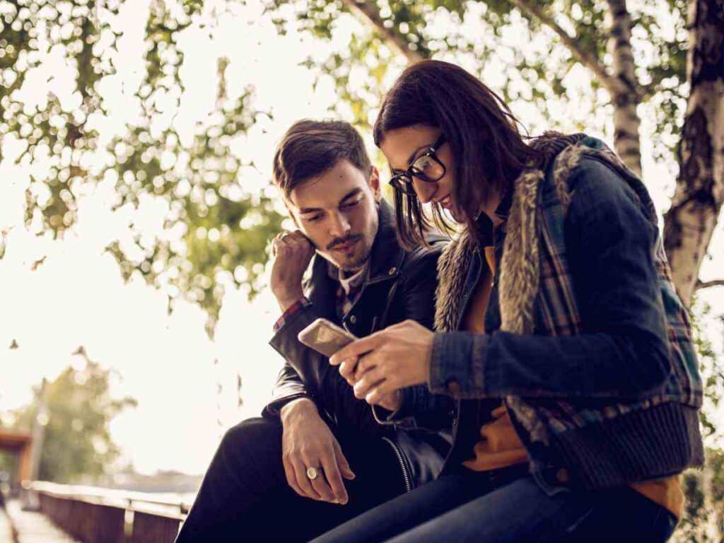 Mulher ensinando como funciona o app de namoro para seu amigo.